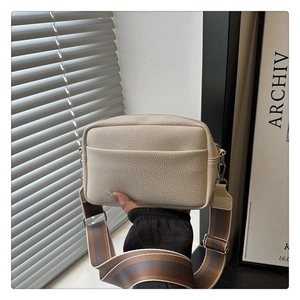 Detail of off-white lychee pattern PU leather crossbody bag with striped wide shoulder strap