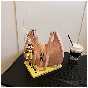 Detail of pink pebbled leather dumpling bag with cute doll charm and silver clasp