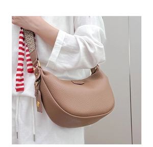 Detail of khaki dumpling bag with lychee grain leather and patterned woven wide strap