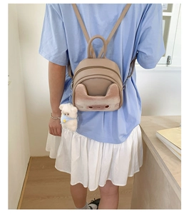 Rear view of a model wearing the beige cat-themed mini backpack with a bear plush charm