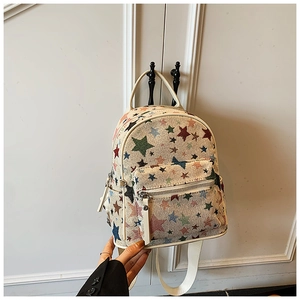 Detail of white canvas mini backpack featuring colorful star patterns and zipper pocket