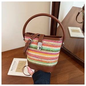 Detailed close-up of rainbow straw bucket bag with leather handles and metal clasp