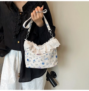 Detailed close-up of floral shoulder bag featuring elegant white lace trim and blue flower print
