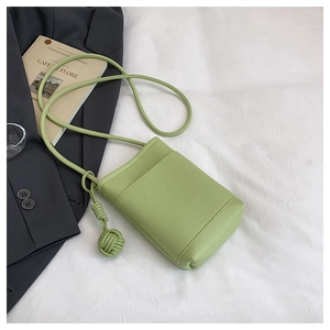 Detail of light green pebble leather phone bag with woven knot strap on white fabric
