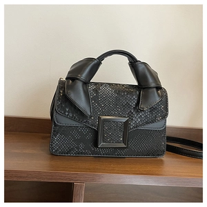Detailed view of black snake embossed leather bag with large square buckle and knotted handle