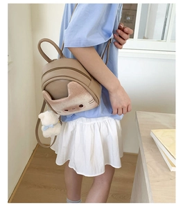 Detailed back view of a khaki cat-shaped mini backpack with a plush bear keychain