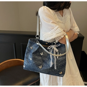 Detail of blue denim tote bag with silver butterflies, lace trim and pearl bow charm