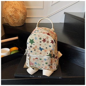 Detail of canvas mini backpack with colorful star pattern on a stack of books