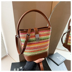 Detail of colorful woven straw bucket bag with brown leather handles and silver twist lock