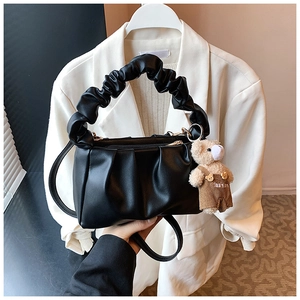 Detail of pleated black underarm bag with cloud handle and cute bear charm accent