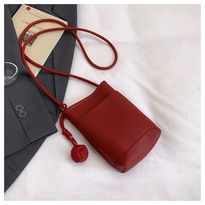 Close-up of a burgundy lychee grain leather mini bag with a round rope strap detail