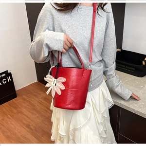 Detail of red bucket bag with silk flower charm and textured leather finish