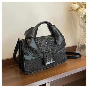 Detail of black snake pattern handbag with vintage buckle and knotted top handle
