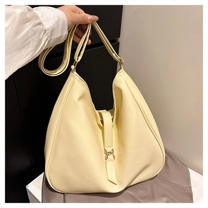 Close-up of cream faux leather hobo tote bag featuring a decorative metal strap buckle