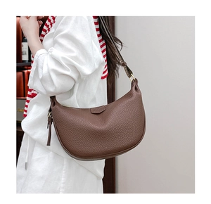 Detailed texture of brown pebble leather on a crescent crossbody bag worn by a model