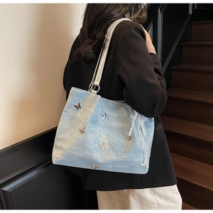 Detail of light blue glitter tote bag with 3D metal butterflies and pearl lace charm