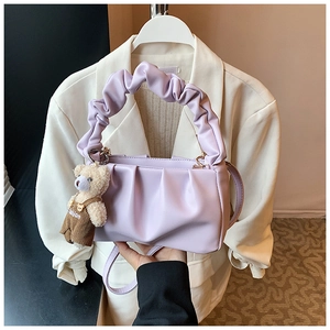 Detail of lavender pleated handbag featuring a cute teddy bear charm and soft cloud handle