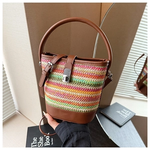 Detail of multi-color woven straw bucket bag with brown leather trim and metal lock