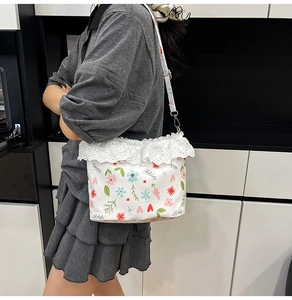 Detail view of floral crossbody bag with white lace edges and adjustable strap on a model