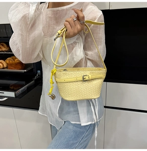 Dettaglio della borsa a tracolla in pelle intrecciata gialla tenuta in mano in interni