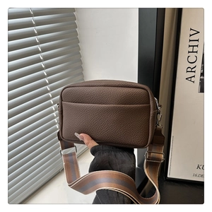 Detail of dark brown litchi pattern PU leather crossbody bag with wide striped strap