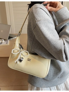 Pale yellow crescent dumpling bag with pearl bow charm and metal logo on strap
