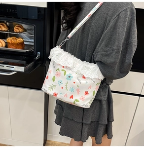 Floral shoulder bag with lace trim detail and colorful print pattern shown on a model