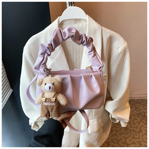 Detail of lavender pleated cloud bag featuring a cute brown plush bear charm and soft PU folds