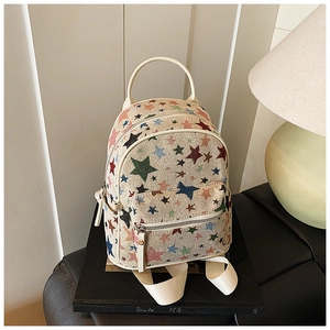 Detail of cream canvas backpack with colorful star pattern on a book with soft lighting