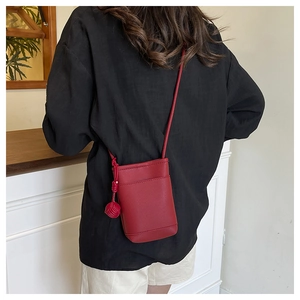 Red lychee leather mini crossbody bag with spherical charm shown on model's back