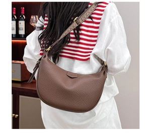 Close-up of brown pebbled leather dumpling bag with bohemian woven strap worn crossbody