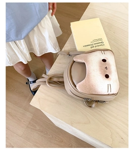 Detail view of a cute cat-themed mini backpack on a wood background with a child nearby