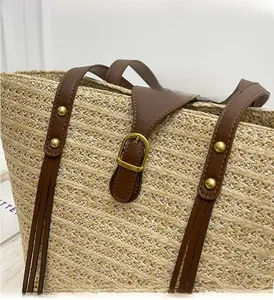 Detail of woven straw tote texture with brown leather strap and golden metal hardware