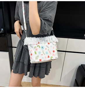 Detail of floral canvas shoulder bag featuring intricate lace trim and metal hook strap