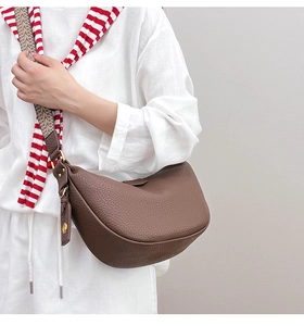 Close-up of brown lychee grain leather dumpling bag with wide geometric strap