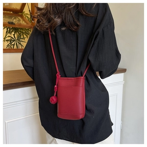 Detailed back view of a red mini crossbody bag with a decorative woven ball charm