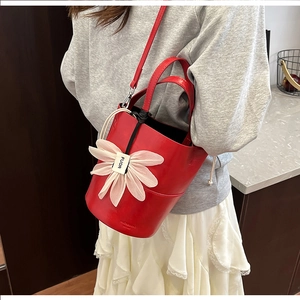 Detailed view of red bucket bag with large floral applique and branded engraving
