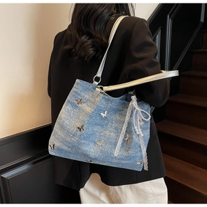 Detail of blue denim tote bag with silver butterfly charms and lace pearl pendants