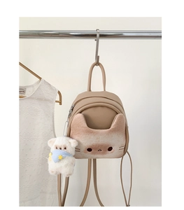 Detail of cute cat-shaped crossbody bag with soft plush bear charm and faux leather texture
