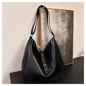 Detail of black faux leather tote bag with smooth texture and metallic buckle closure