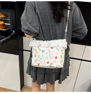 Detail of floral shoulder bag with delicate white lace trim and adjustable crossbody strap