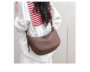 Detail of dark brown pebbled leather dumpling bag featuring sleek gold metal buckles