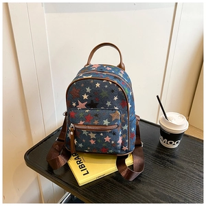 Detail of blue denim backpack with colorful star prints and brown leather handle