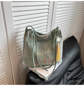 Detailed close-up of light green silk embroidery bucket bag with landscape pattern and tassel