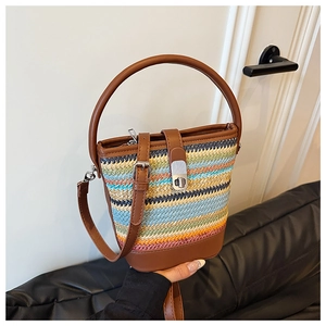 Detailed view of rainbow striped woven bucket bag with brown leather handles and lock