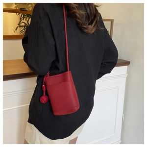 Close-up of a red leather crossbody phone bag with tassel detail on a female model