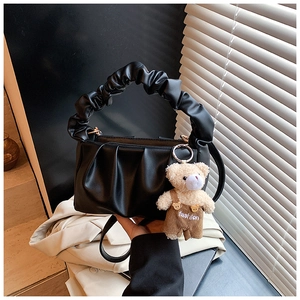 Detail of black pleated shoulder bag with a cute bear charm and metal zipper