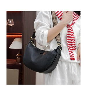 Detail of black pebbled leather dumpling bag with decorative woven strap and gold hardware