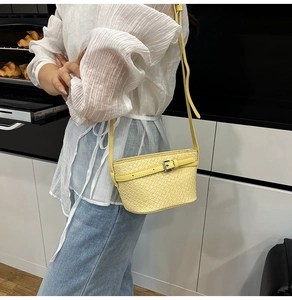 Dettaglio della borsa a secchiello intrecciata giallo chiaro con fibbie in metallo