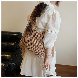 Détail du sac à bandoulière en maille ajourée avec franges et breloque en bois